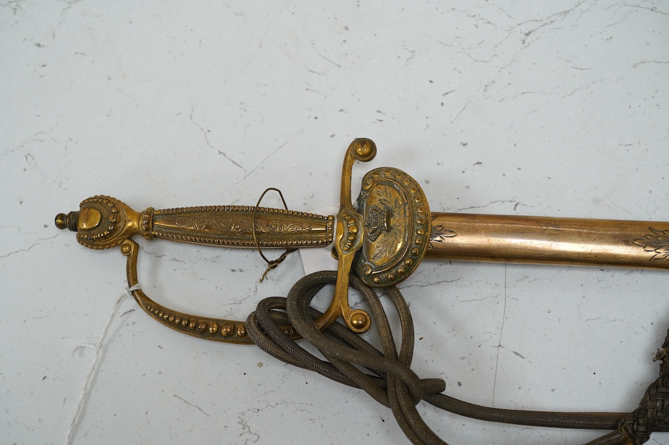 A late Victorian court sword gilt brass hilt with crown on guard, beaded edges, bullion dress knots, in its leather scabbard, blade 78cm. Condition - fair to good